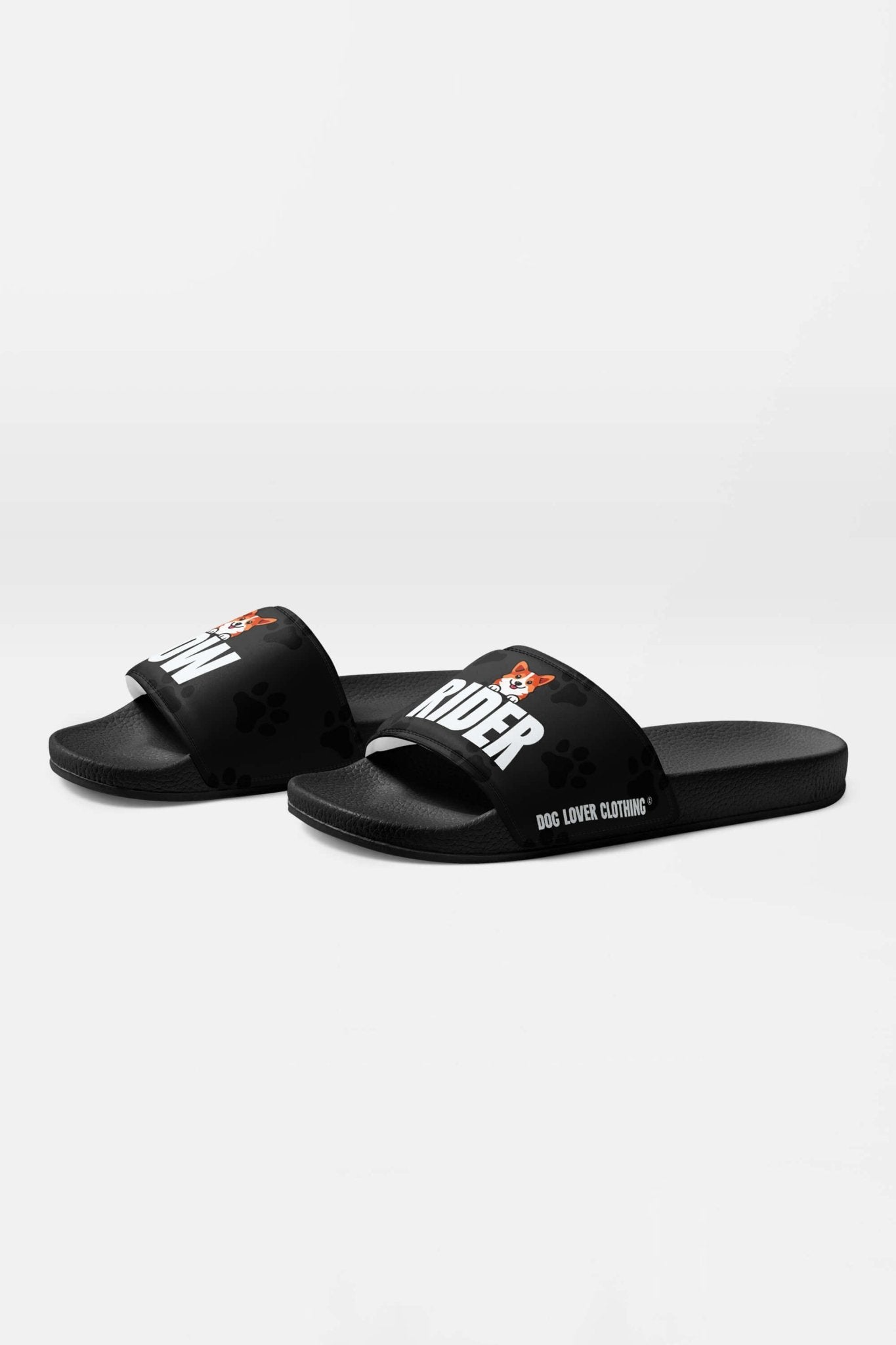 The Mighty Corgi Rider Slides by Dogloverclothing.com feature black straps with RIDER in white and an orange corgi face, plus a paw print pattern. Durable and comfy, they’re ideal for dog lovers seeking stylish footwear.