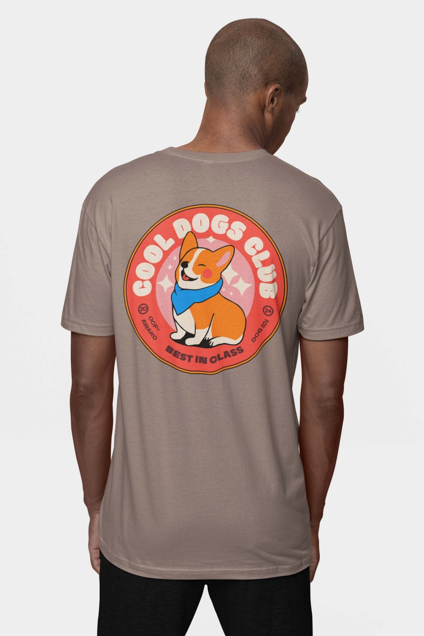 A dog lover wears a Cool Dogs Club Unisex Hype T-Shirt by Dogloverclothing.com, featuring the clubs logo. On the back, a circular graphic depicts a smiling corgi with a blue bandana and BEST IN CLASS in bold.