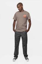 A person stands with hands in pockets, wearing the Cool Dogs Club Unisex Hype T-Shirt by Dogloverclothing.com featuring a Cool Dogs Club logo on the chest. They pair it with dark pants and black sneakers with white soles against a plain white background, looking downward.