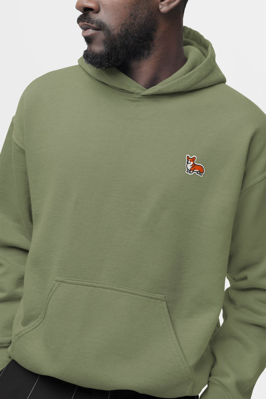 Man in the olive green Corgi Sidekick Embroidered Hoodie from WOOF with the chest embroidery