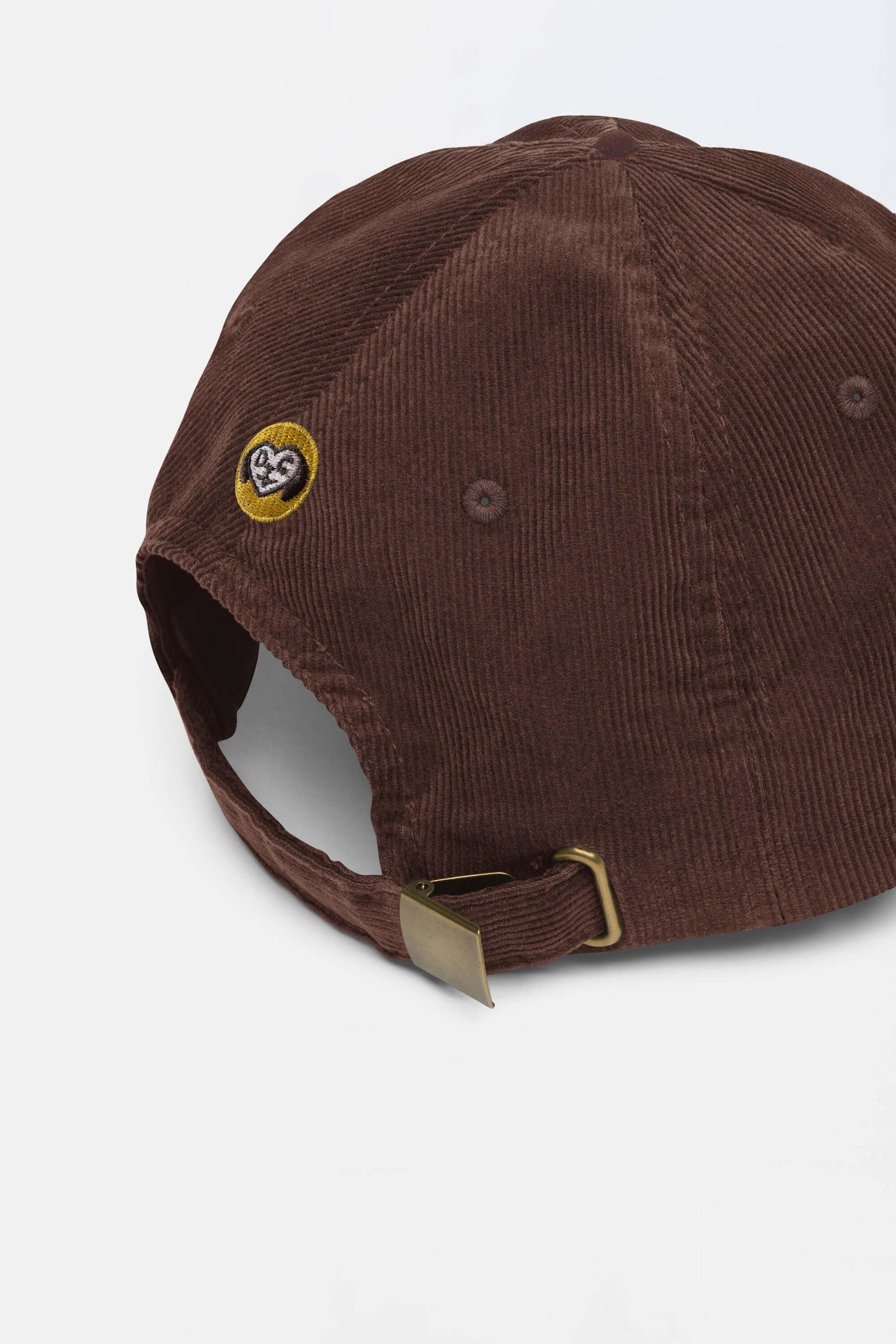 The Limited Dog Lover Corduroy Cap by Dogloverclothing.com is a vintage brown cap with a brass buckle strap and a small embroidered dog face patch near the back opening.