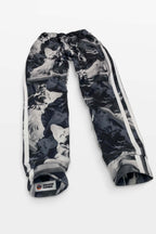 Corgi Supreme Tribute Joggers from Dogloverclothing.com feature a gray wolf pattern, white side stripes, and an elastic waistband for comfort. Crafted from recycled materials with a DOG LOVE CLOTHING label and paw print logo, these sweatpants offer style and eco-friendly appeal.