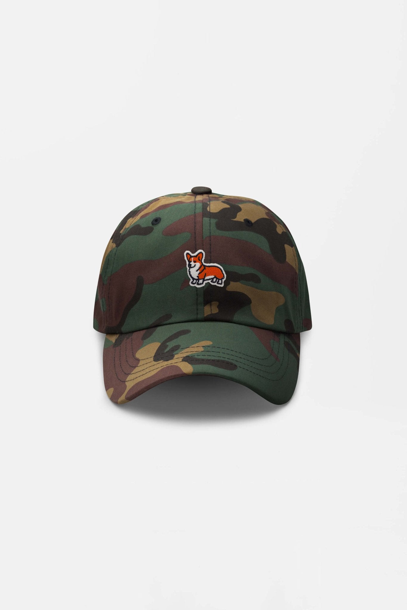 The Iconic Corgi Cap by Dogloverclothing.com is a camouflage baseball hat with a small embroidered corgi patch on the front, perfect for showing off your love of unique dog headgear. Displayed against a plain white background.