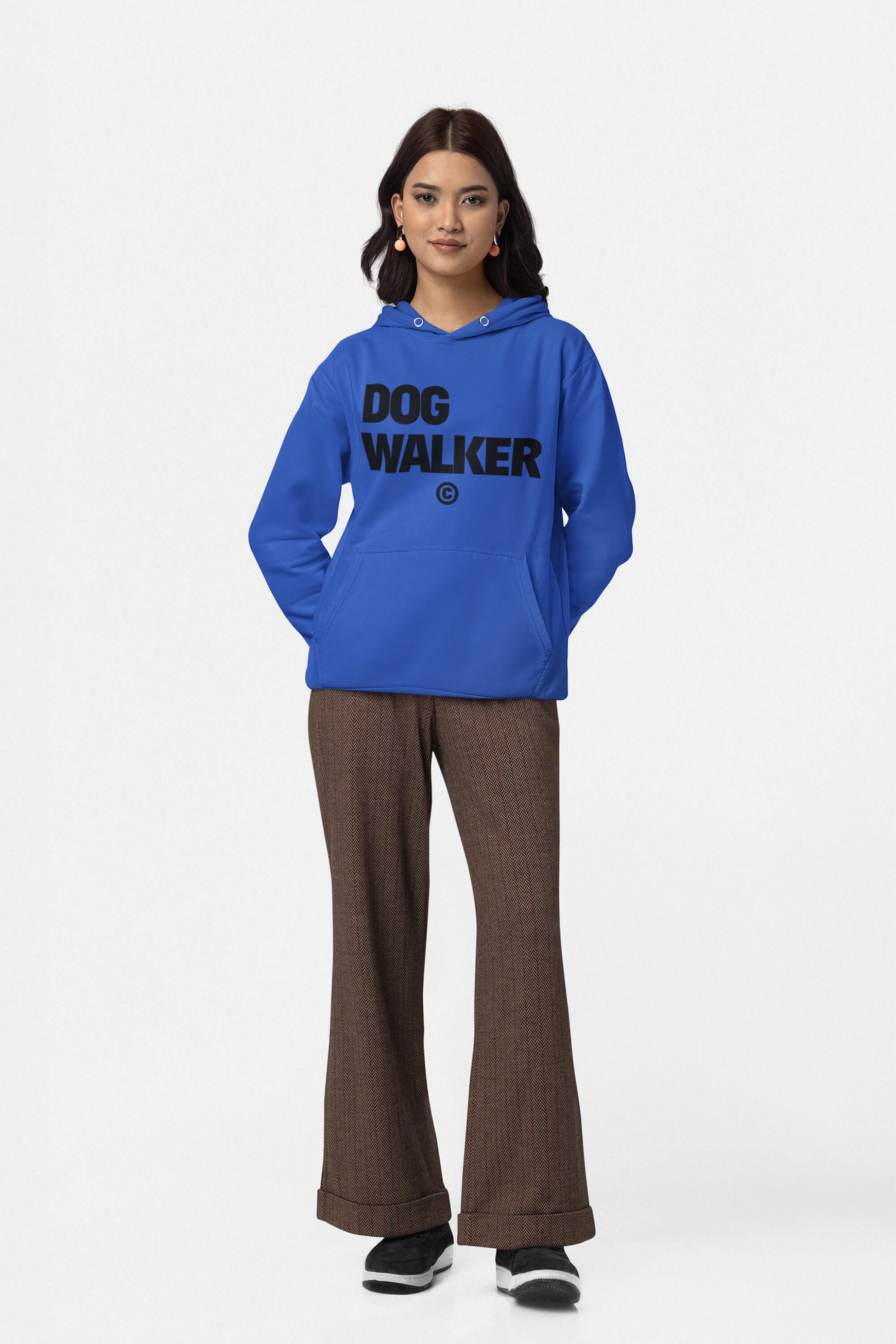 Against a plain background, a person wears the Unisex Dog Walker© Premium Hoodie from Dogloverclothing.com, featuring DOG WALKER in bold black letters. Paired with brown checkered pants and black shoes, their hands rest in the hoodie pockets as they face forward, ready for everyday adventures.