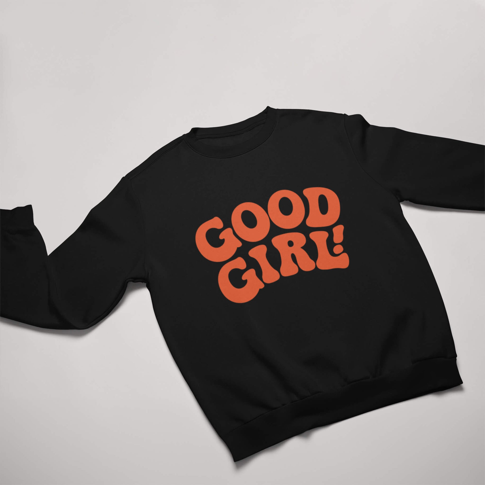 Displayed against a light grey backdrop, the Good Girl Sweatshirt from Dogloverclothing.com features GOOD GIRL! in bold, orange retro-style letters on its flat black surface. This stylish pick is perfect for dog lovers seeking themed apparel.