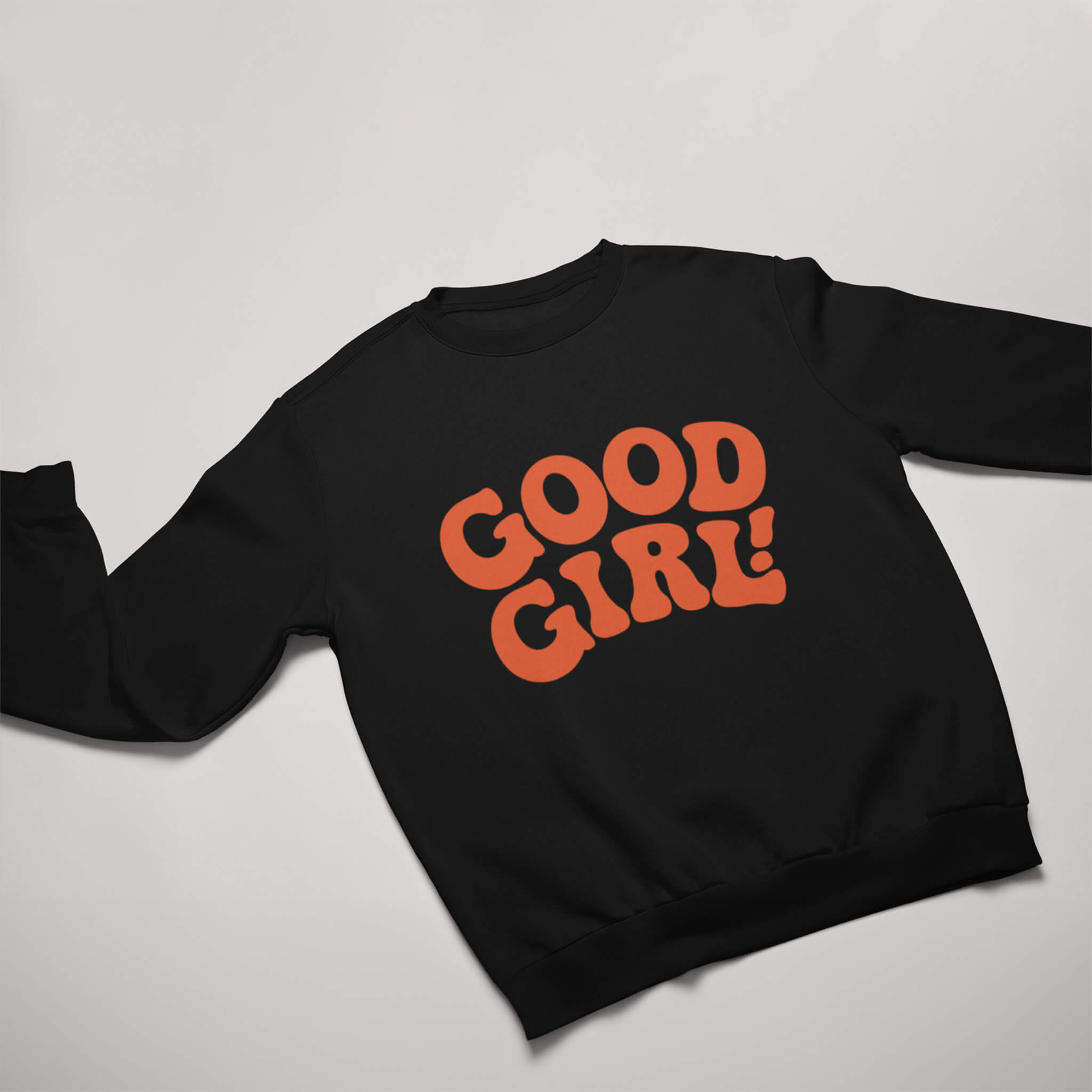 Displayed against a light grey backdrop, the Good Girl Sweatshirt from Dogloverclothing.com features GOOD GIRL! in bold, orange retro-style letters on its flat black surface. This stylish pick is perfect for dog lovers seeking themed apparel.
