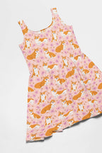 The Adorable Corgi Summer Dress from Dogloverclothing.com features a sleeveless skater design with a flared skirt, adorned with playful corgis against a pink background decorated with hearts and bones, artfully arranged flat on a white surface.