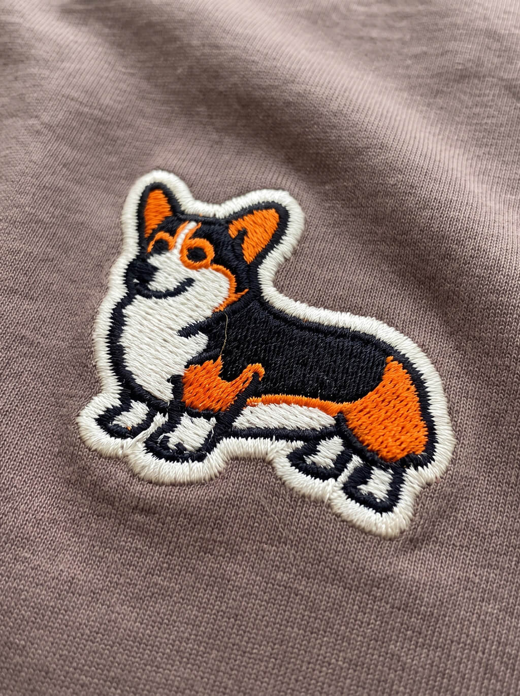 Close up of the tricolor corgi embroidery on the brown T-Shirt from WOOF