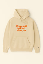 The Bold My Dog And I Talk Embroidered Hoodie from Dogloverclothing.com is a beige, classic-fit hoodie with a front pocket and My dog and I talk sh*t about you embroidered in orange on the front.