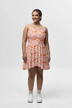 An upbeat individual dons Dogloverclothing.coms Adorable Corgi Summer Dress, standing against a plain white backdrop. White shoes and beige socks complete the ensemble, radiating delightful charm.