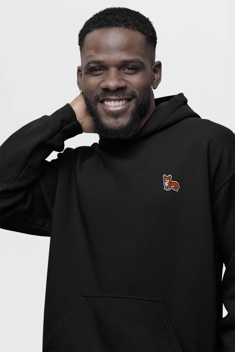Bearded man in the black Classic Corgi Sidekick Embroidered Hoodie from WOOF with the chest embroidery