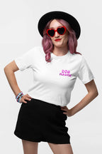 A person with pink hair, wearing a black hat and heart-shaped red sunglasses, confidently rocks a Dogloverclothing.com Ultra Soft Dog Mama Balloon T-Shirt. Black shorts complement the look as they pose with one hand on their hip, colorful bracelets adding flair to one wrist.