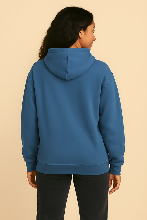A person with long, dark, wavy hair is shown from the back, wearing the ultra-soft Dog Mom Hoodie by Dogloverclothing.com and black pants, standing against a plain beige background.