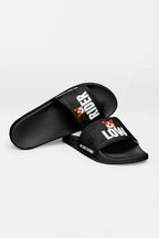 A pair of black Mighty Corgi Rider Slides from Dogloverclothing.com—one flat, one on its side—feature RIDER LOW in white and a fox head on the straps, crafted from durable materials for comfortable wear.