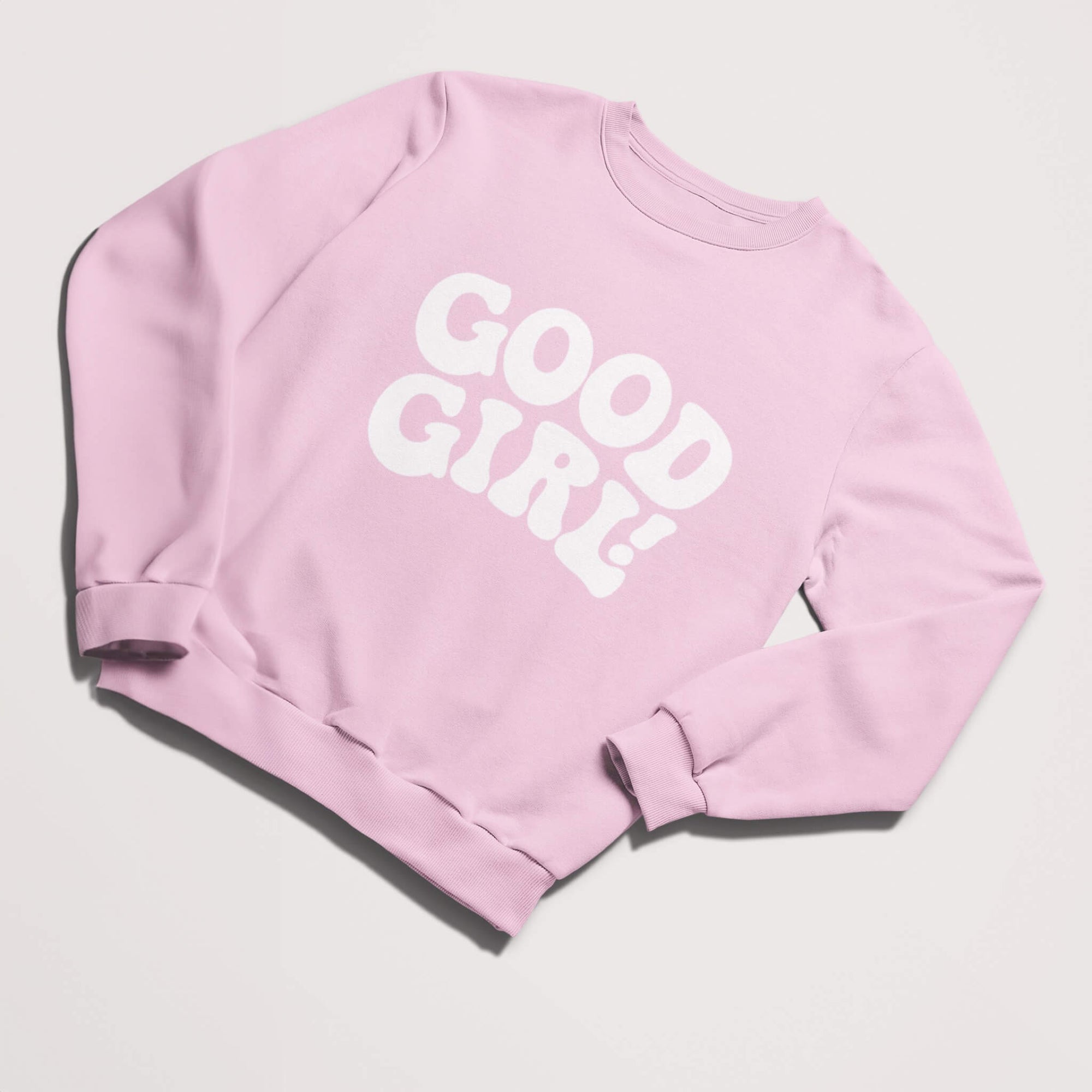 The Good Girl Sweatshirt by Dogloverclothing.com is light pink with GOOD GIRL! in bold white letters. Perfect for dog lovers, this piece is displayed on a plain white background and is a must-have addition to your dog-themed collection.