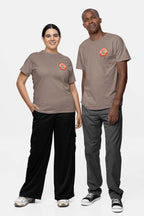 Two people wear matching taupe Cool Dogs Club Unisex Hype T-Shirts from Dogloverclothing.com with colorful logos on the left chest. The person on the left wears black pants, while the one on the right has gray pants and black sneakers. Theyre against a plain background, representing the Cool Dogs Club.