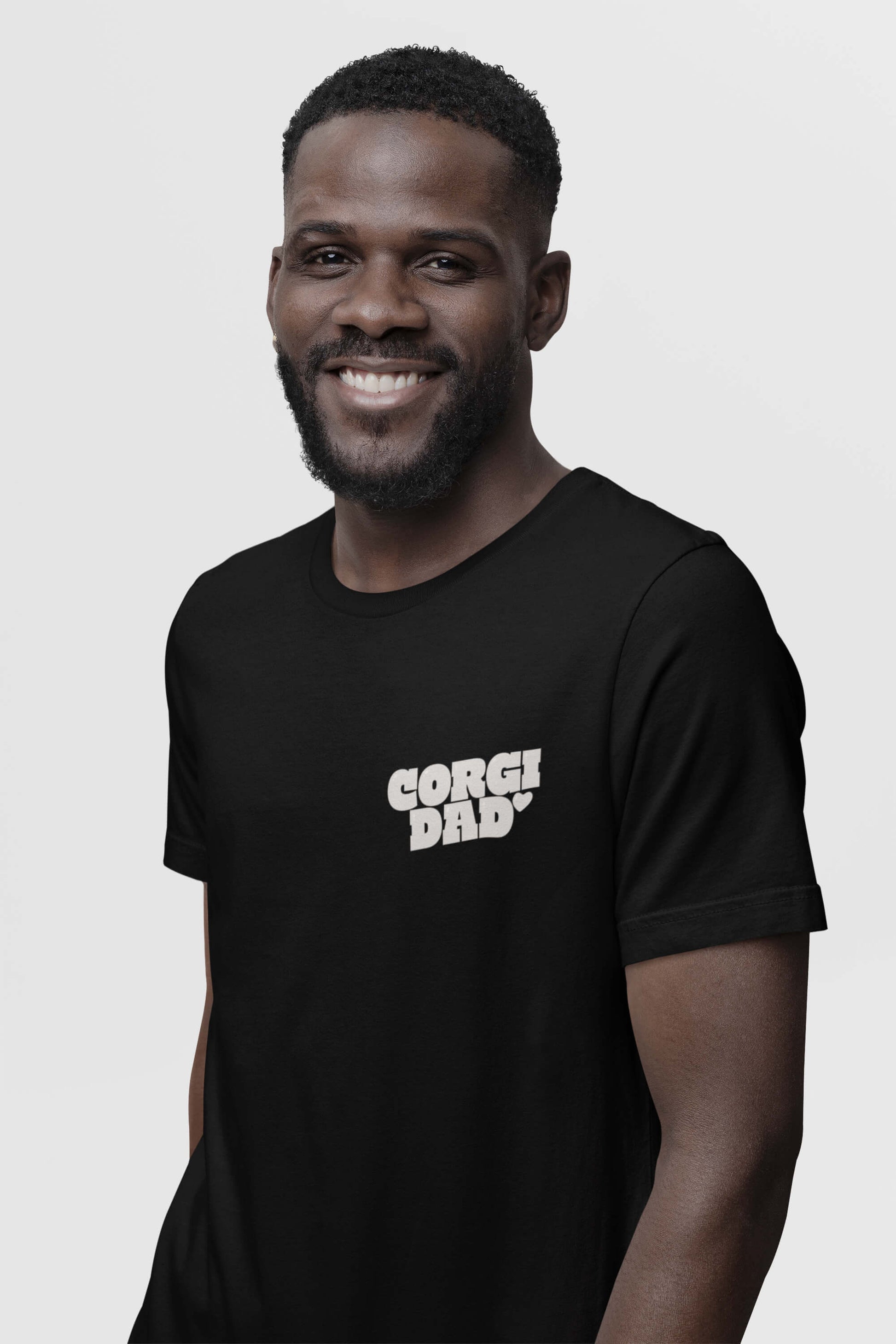 Bearded man in a Corgi Dad Ultimate Tribute T-Shirt by Dogloverclothing.com, ideal for dog lovers, stands against a plain backdrop.