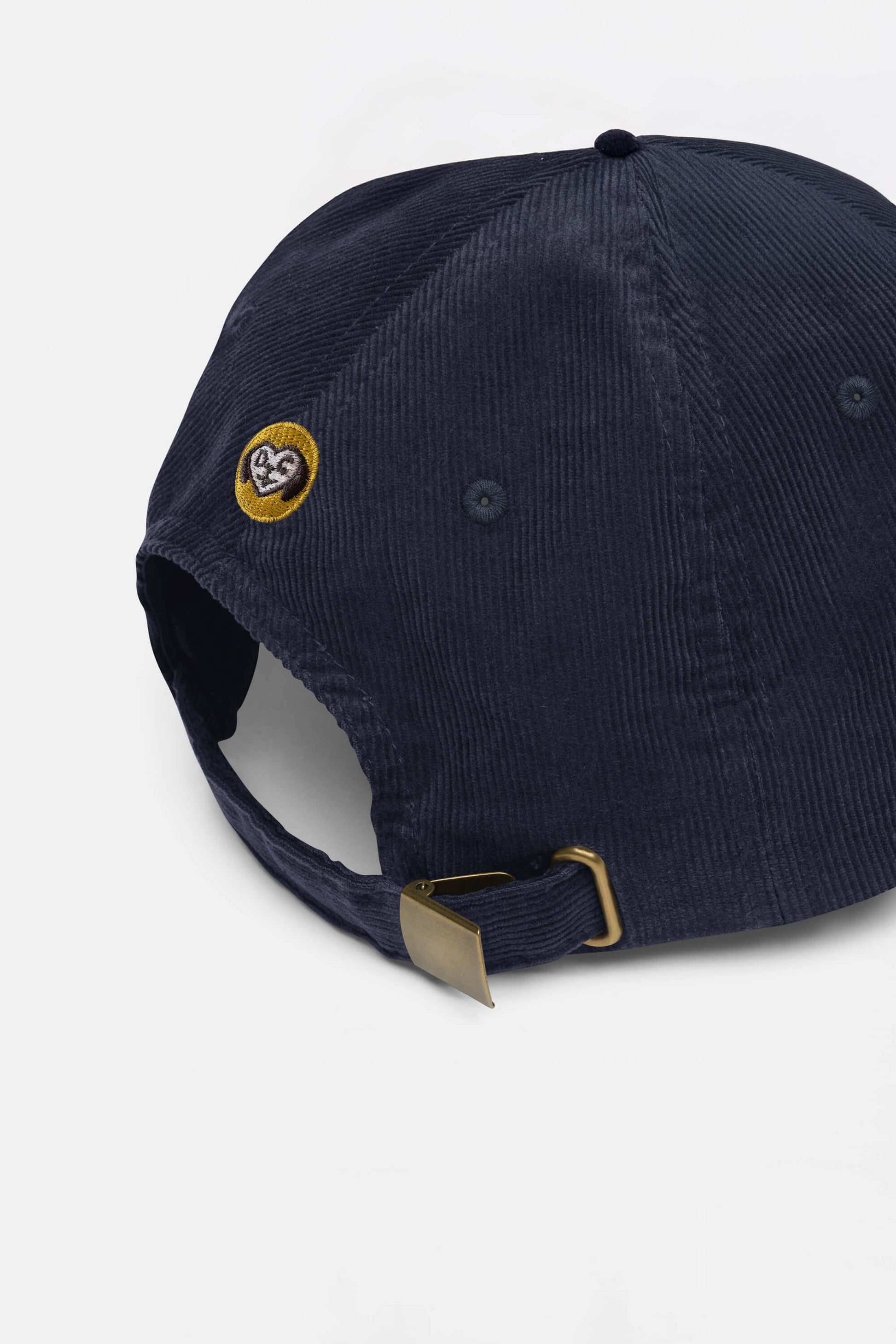 The Limited Dog Lover Corduroy Cap by Dogloverclothing.com, shown from the back in navy blue, features a brass buckle adjustable strap and a small yellow-outlined embroidered heart patch on the left side.