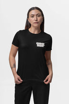 A long-haired person with tattoos and a neutral expression stands against a plain white background, wearing black pants and Dogloverclothing.com’s premium fabric Corgi Mom Ultimate Tribute T-Shirt in black, epitomizing stylish appeal for dog enthusiasts.