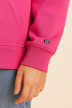 A close-up shows a person in Dogloverclothing.com’s Bold My Dog And I Talk Embroidered Hoodie, featuring premium bright pink fabric, a small panda face embroidered on the sleeve, and paired with light blue jeans for all-day comfort.