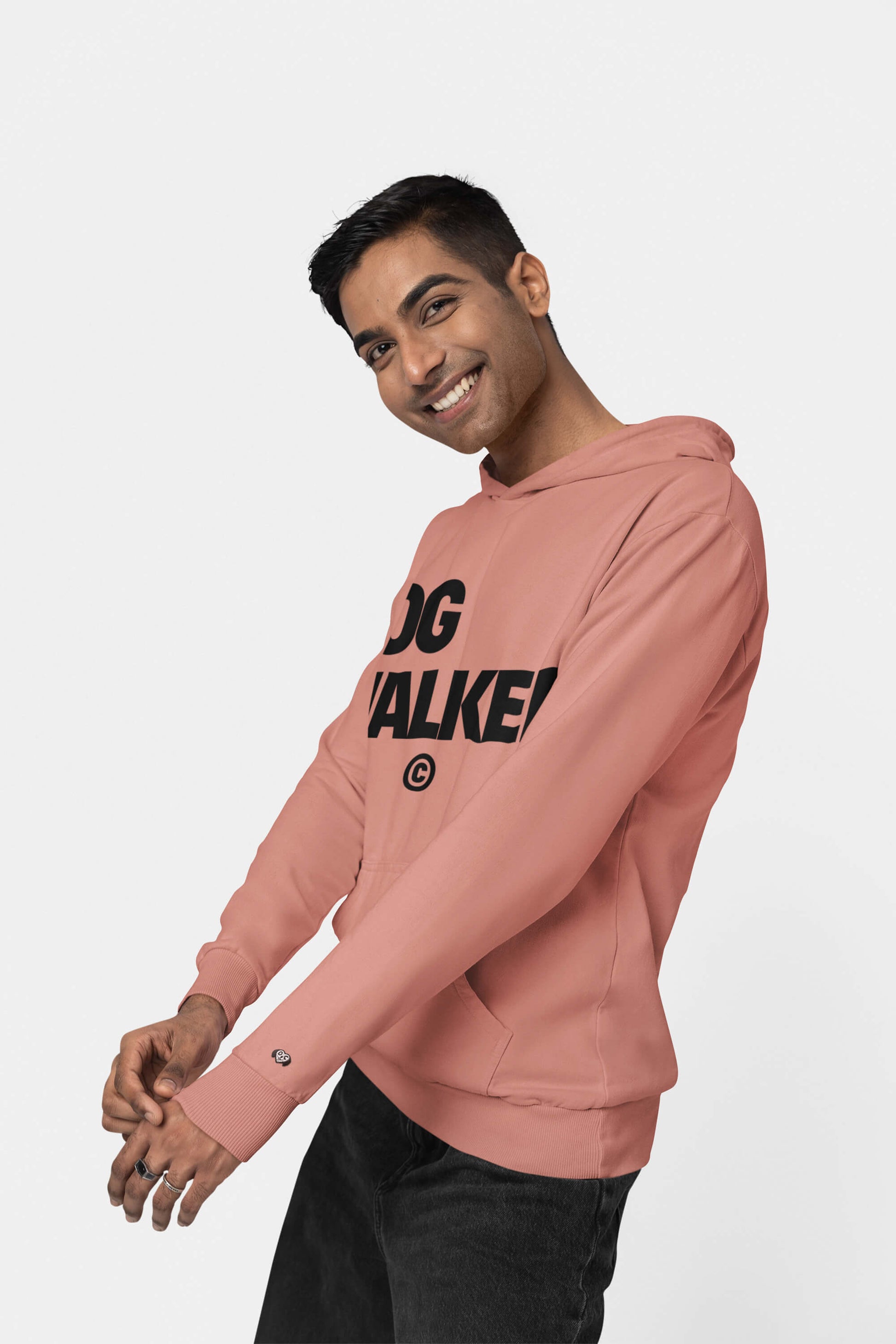 A smiling person poses playfully in an Unisex Dog Walker© Premium Hoodie from Dogloverclothing.com, showcasing their love for everyday adventures. The vibrant pink hoodie stands out against the plain white background, perfectly complementing their short dark hair and dark pants.