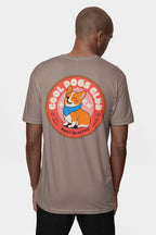 A dog lover wears a Cool Dogs Club Unisex Hype T-Shirt by Dogloverclothing.com, featuring the clubs logo. On the back, a circular graphic depicts a smiling corgi with a blue bandana and BEST IN CLASS in bold.