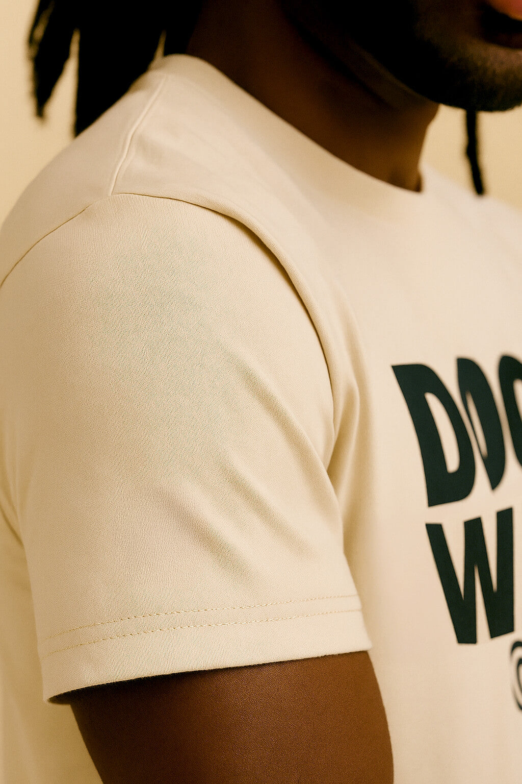 Close-up of a person wearing the Relaxed Dog Walker© Unisex T-Shirt by Dogloverclothing.com in light beige with black text, featuring a relaxed fit—ideal for everyday wear or busy dog walkers; face mostly out of frame.