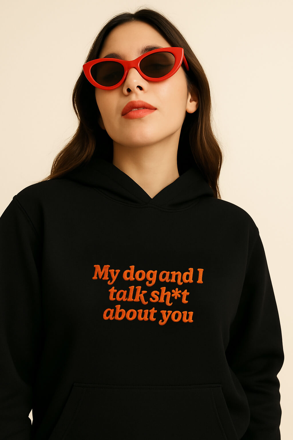 A woman in red cat-eye sunglasses wears the Bold My Dog And I Talk Embroidered Hoodie by Dogloverclothing.com, featuring orange text, against a plain light background.