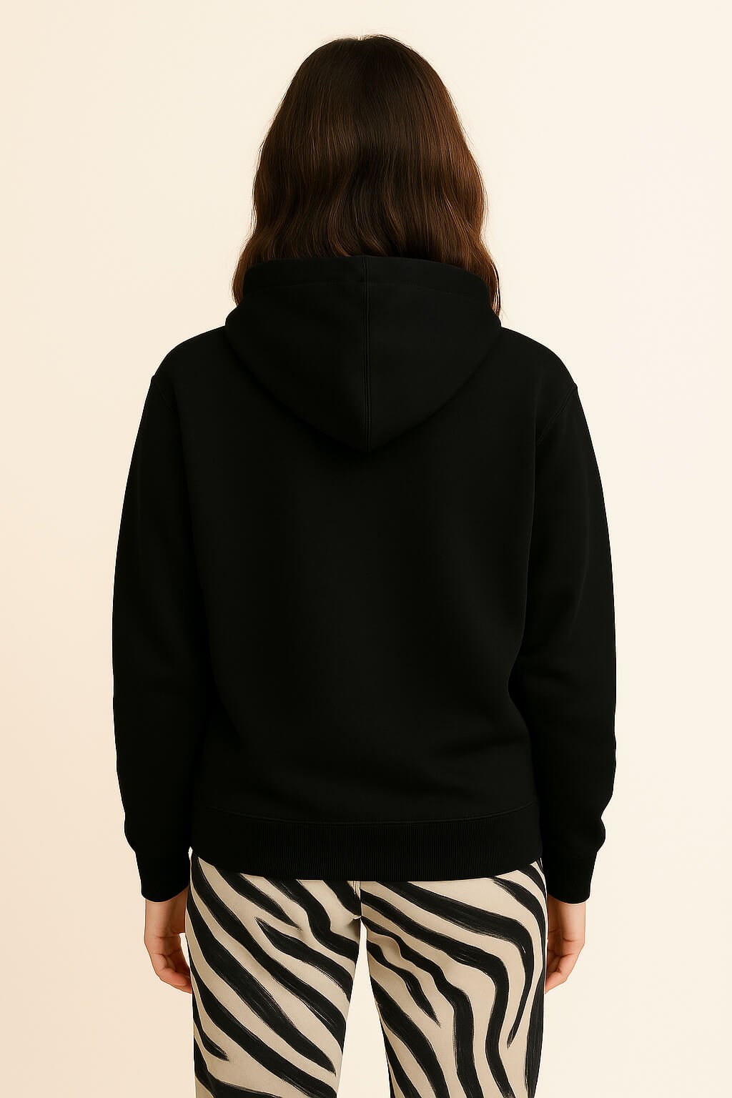 A person with long brown hair is facing away from the camera, wearing the Bold My Dog And I Talk Embroidered Hoodie from Dogloverclothing.com and black-and-white zebra print pants, against a plain light background.