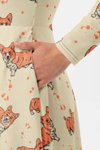 A person models the Cozy Corgi Long Sleeve Midi Dress from Dogloverclothing.com, showcasing an orange corgi pattern. The dress’s side pockets offer functionality with flair. Set against a white background, the fun dog design stands out beautifully.
