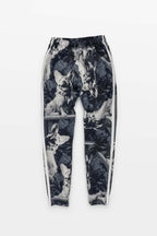 Corgi Supreme Tribute Joggers by Dogloverclothing.com feature a wolf pattern in black and white camouflage, crafted from recycled materials. These eco-friendly joggers have an elastic waistband, white side stripes, and are showcased against a plain white background.