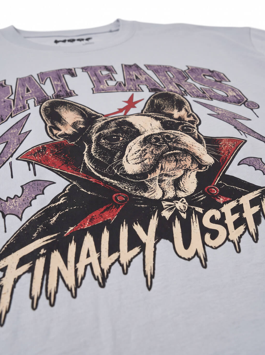 Close-up of the "Bat Ears – Finally Useful" print with a vampire French Bulldog on the Light Washed Denim tee