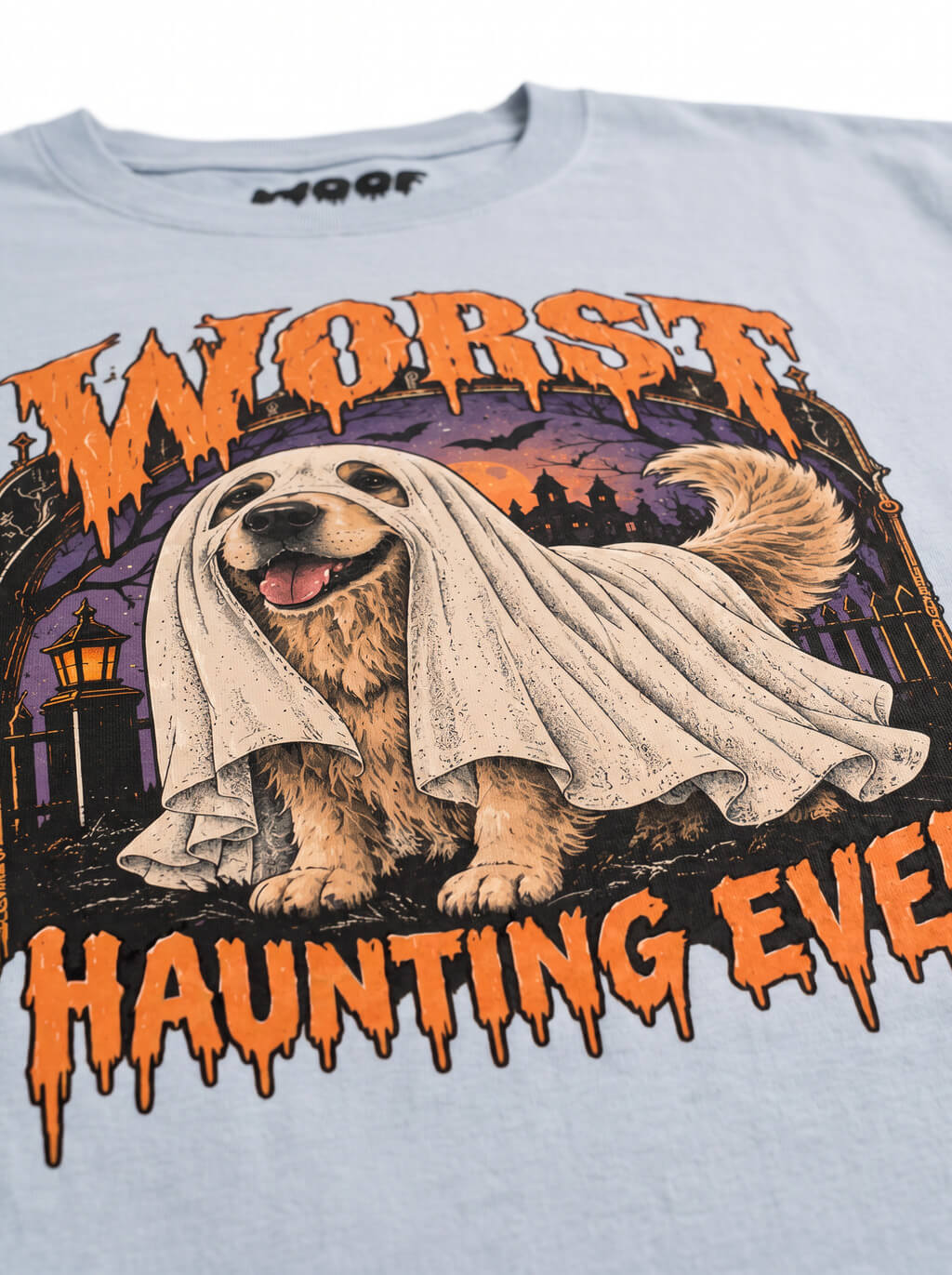 Close-up of the "Worst Haunting Ever" print with a Golden Retriever in a ghost sheet on the Light Washed Denim tee