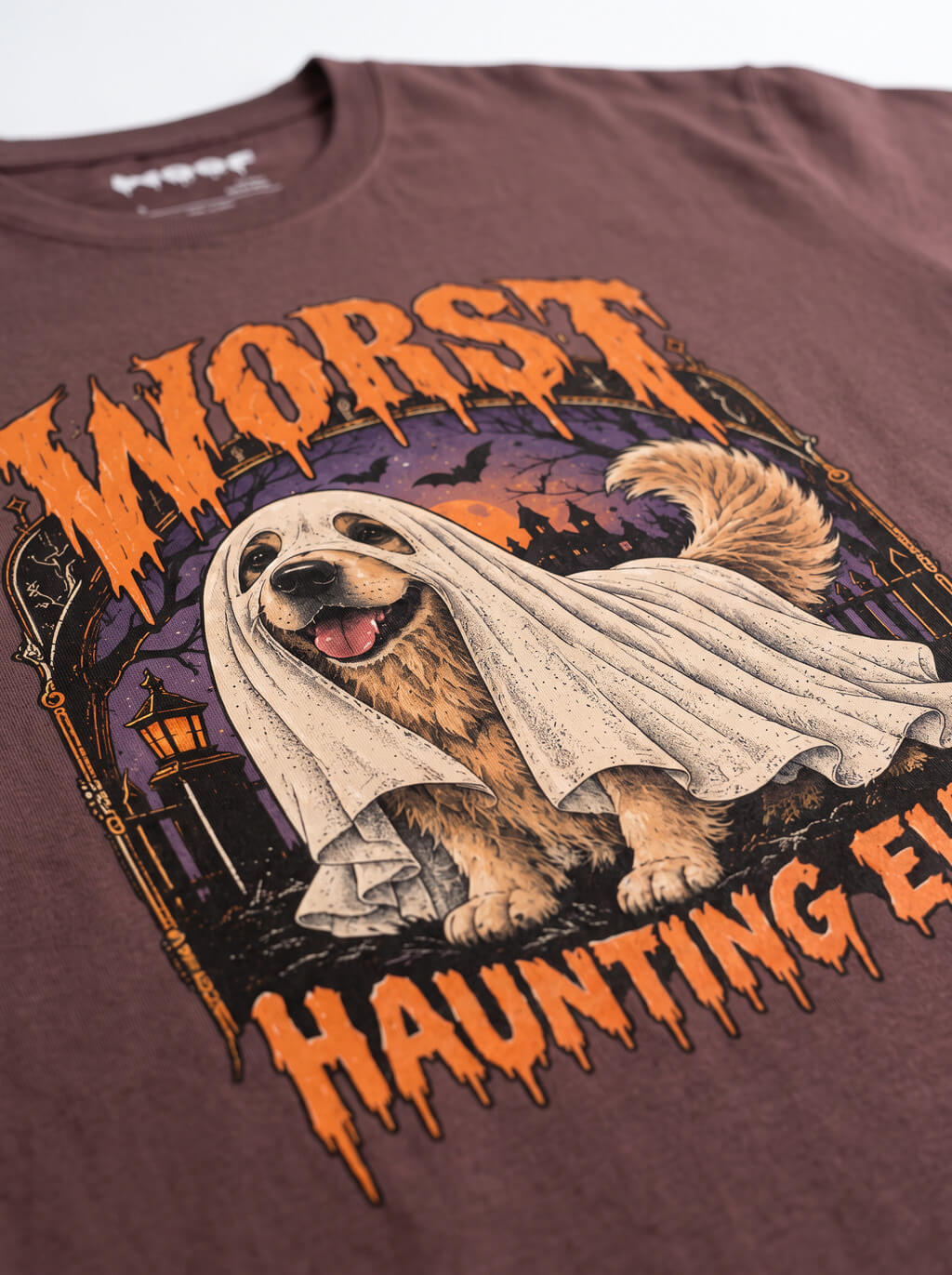 Close-up of the "Worst Haunting Ever" print with a Golden Retriever in a ghost sheet on the Washed Maroon tee