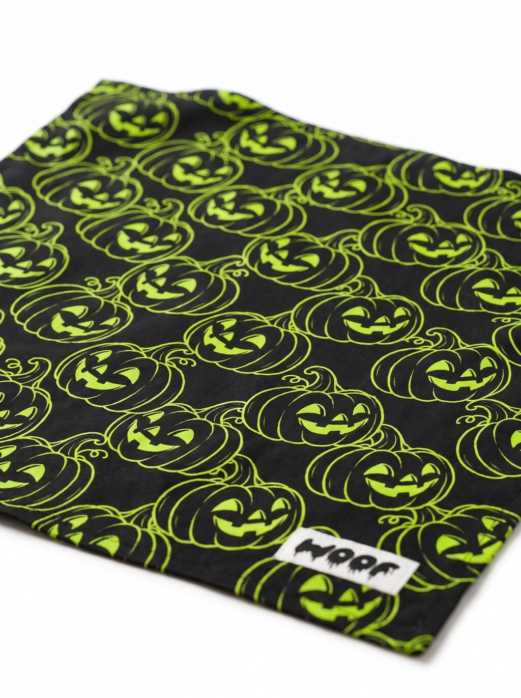 Close-up of the neon green jack-o-lantern pattern on the black Halloween dog bandana