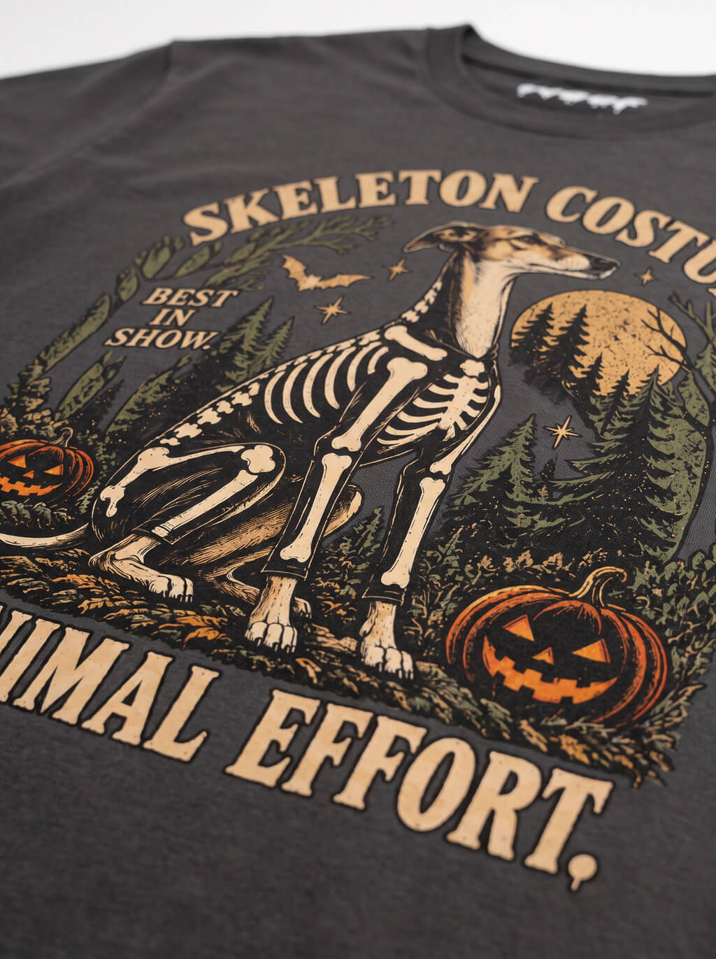 Close-up of the "Skeleton Costume. Minimal Effort." print with a Greyhound in a skeleton costume on the Washed Black tee