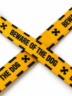 Close-up of the yellow Haunted Hound leash webbing with the black Beware of the Dog lettering and bone icons