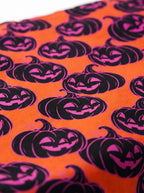 Close-up of the black and pink jack-o-lantern pattern on the orange Halloween dog bandana