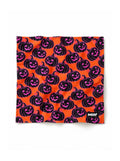 Orange Pumpkin dog bandana in orange with a black and pink jack-o-lantern pattern, laid out flat