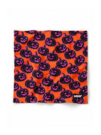 Orange Pumpkin dog bandana in orange with a black and pink jack-o-lantern pattern, laid out flat