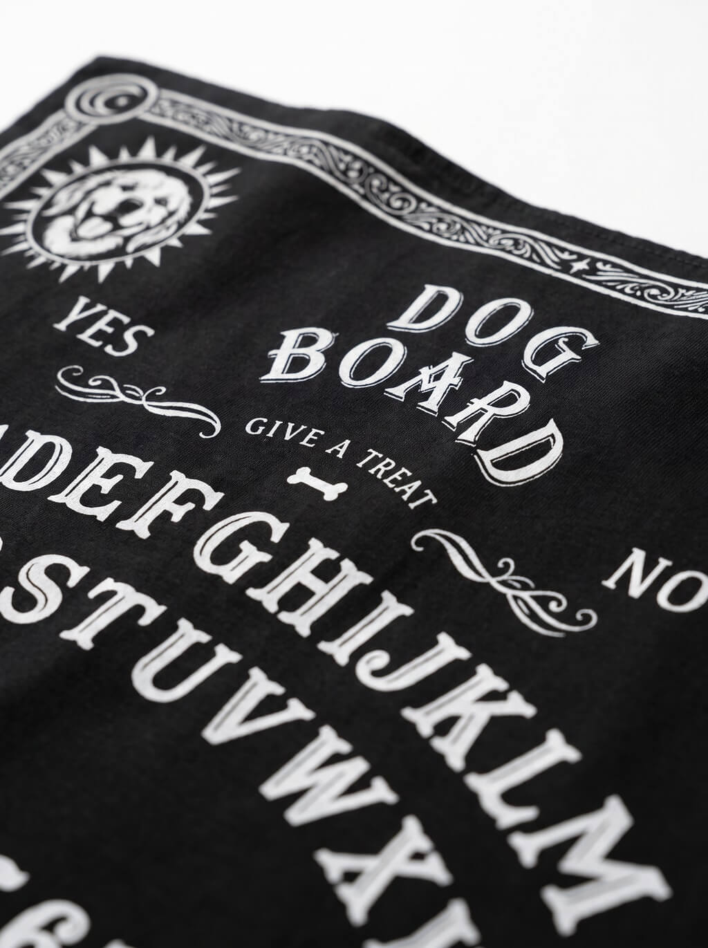 Close-up of the "Dog Board – Give a Treat" print on the black Ouija Board dog bandana