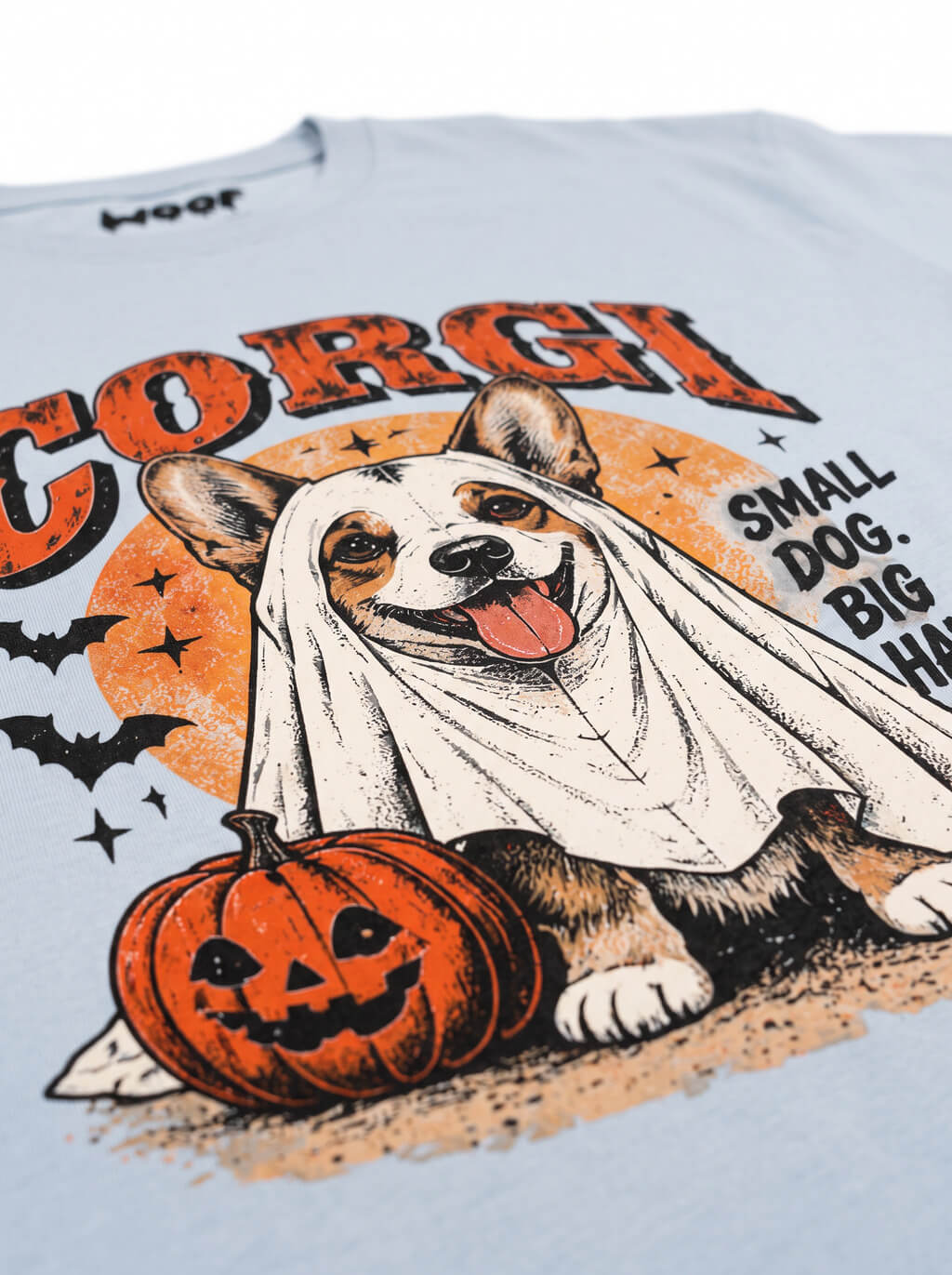 Close-up of the "Corgi – Small Dog, Big Haunts" print with a Corgi in a ghost sheet on the Light Washed Denim tee