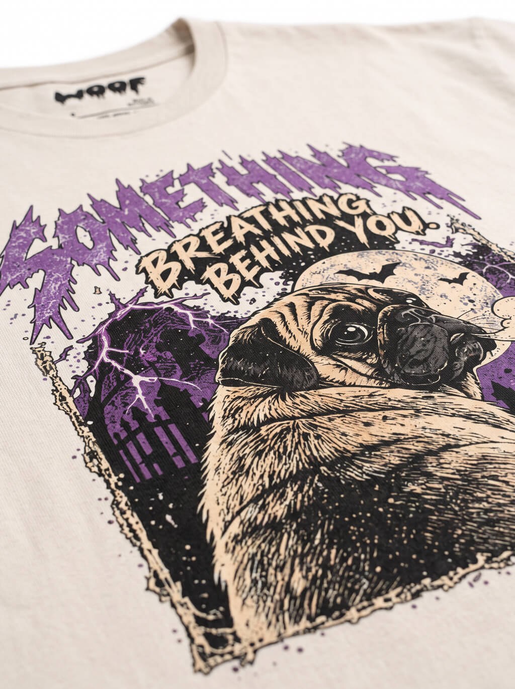 Close-up of the "Something Breathing Behind You" print with a Pug looking back in a spooky graveyard on the Vintage White tee