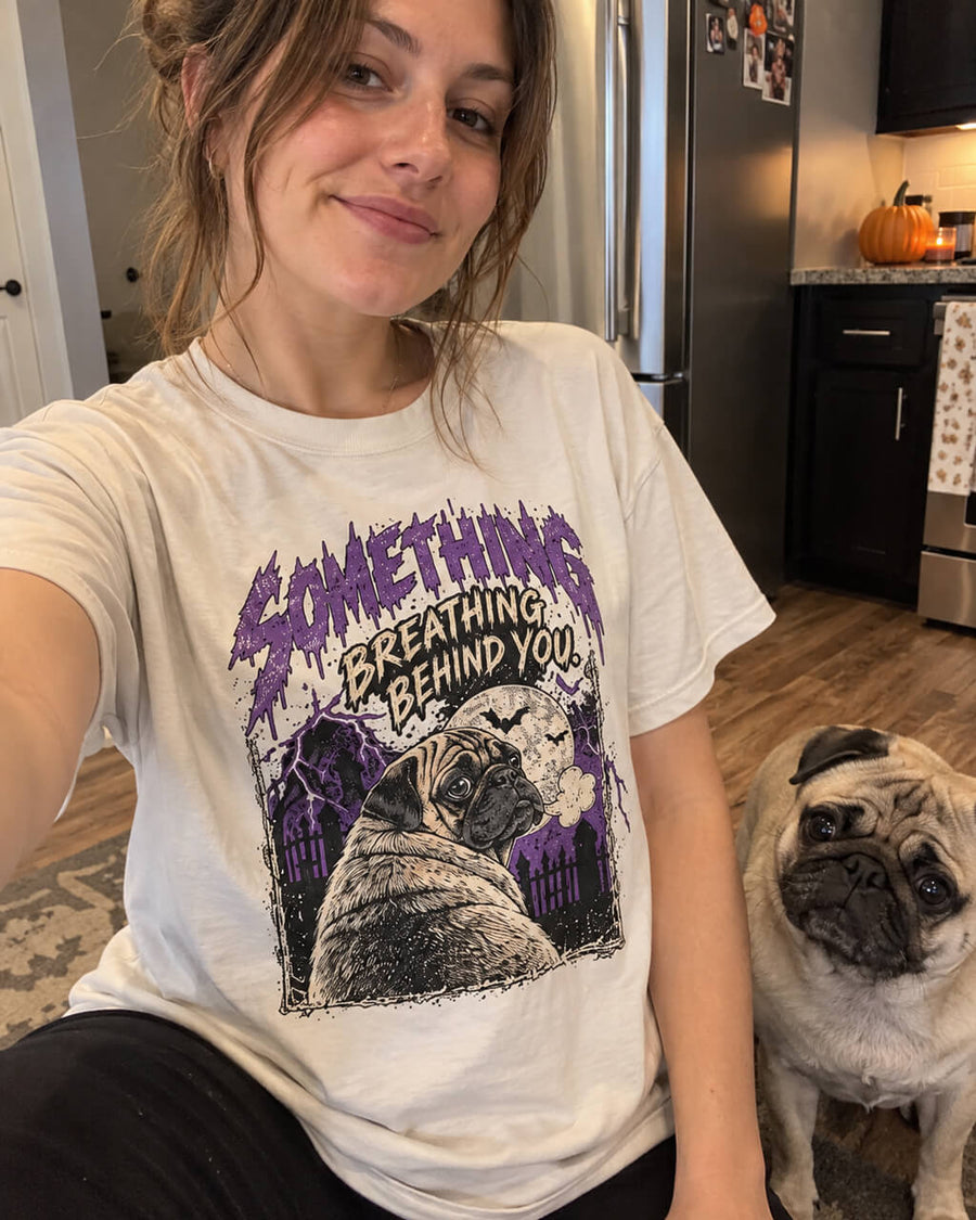 Pug Halloween oversized T-shirt in Vintage White worn by a woman taking a selfie in her kitchen with her Pug