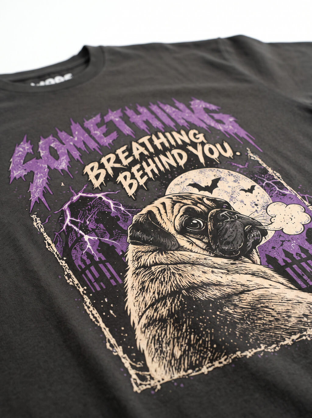 Close-up of the "Something Breathing Behind You" print with a Pug looking back in a spooky graveyard on the Washed Black tee