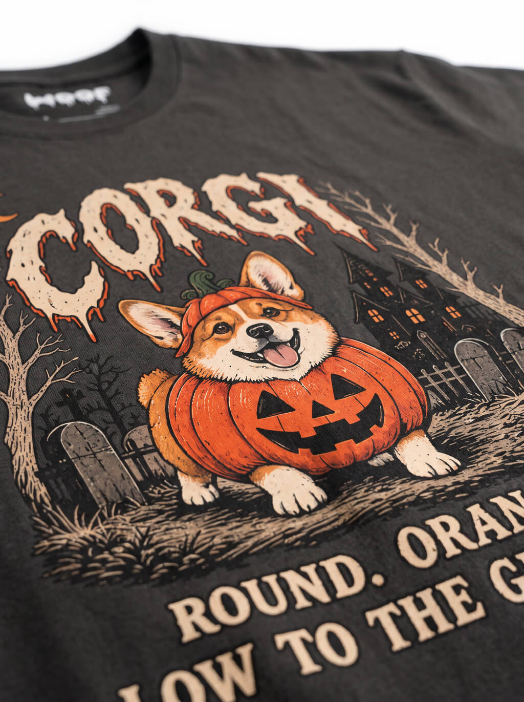 Close-up of the "Corgi – Round. Orange. Low to the Ground." print with a Corgi in a jack-o'-lantern in a graveyard on the Washed Black tee