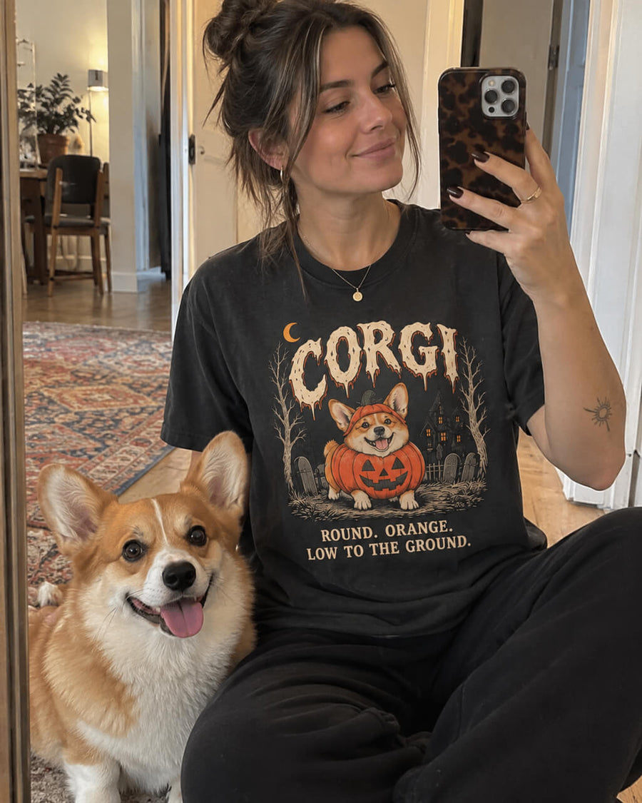 Pumpkin Loaf Corgi oversized Halloween T-shirt in Washed Black worn by a woman taking a mirror selfie with her Corgi