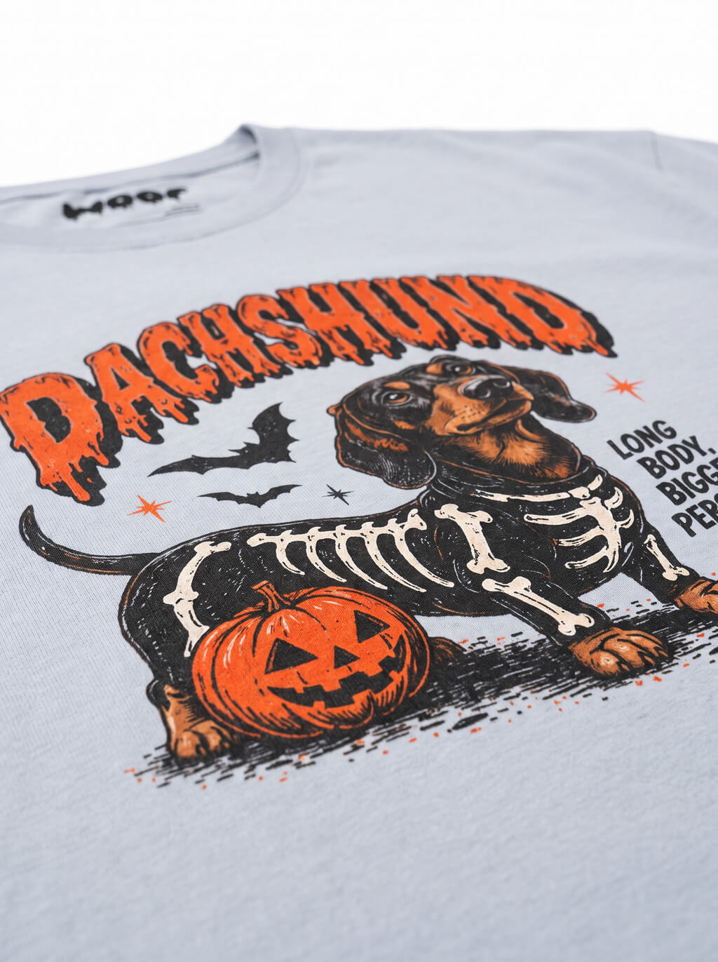 Close-up of the "Dachshund" print with a Dachshund in a skeleton costume with pumpkins on the Light Washed Denim tee