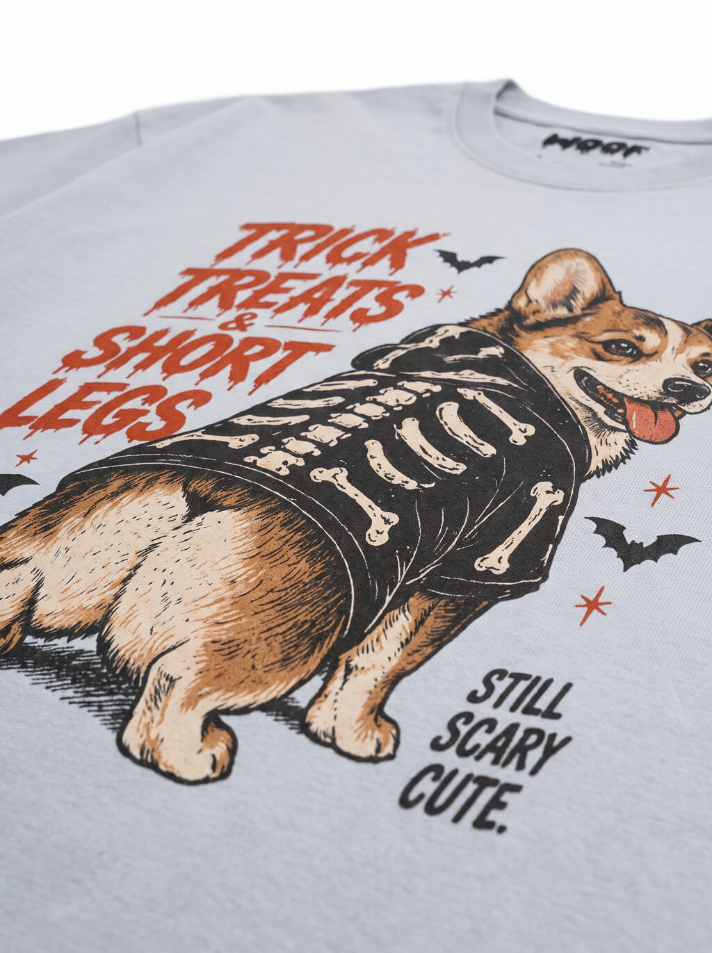 Close-up of the "Trick, Treats & Short Legs" print with a Corgi in a skeleton costume on the Light Washed Denim tee