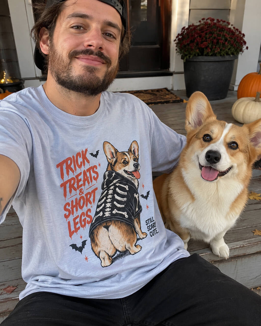 Treat First Corgi oversized Halloween T-shirt in Light Washed Denim worn by a man sitting on a Halloween porch with his Corgi